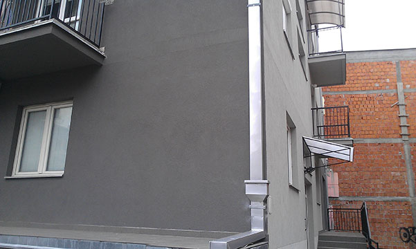 Building facade with terrace, window and vertical gutter flashings.